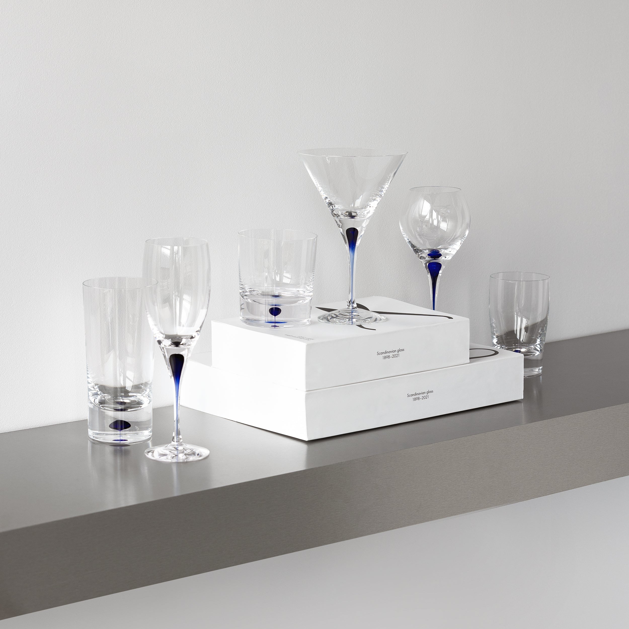 Set of Orrefors glassware including tumblers and a martini glass on a white surface with a gray background