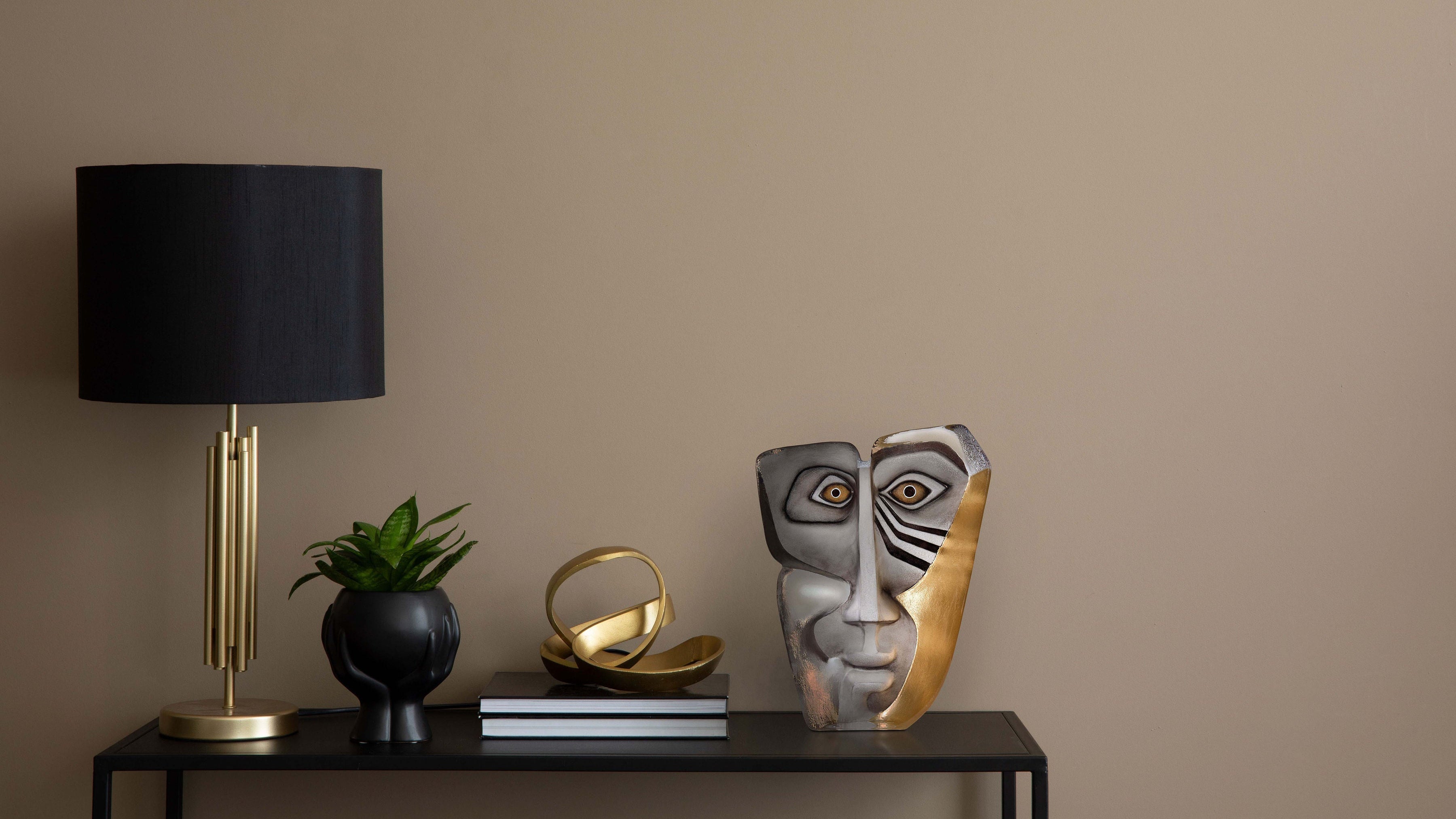 Glass face sculpture by Maleras Sweden on a table against a beige wall.