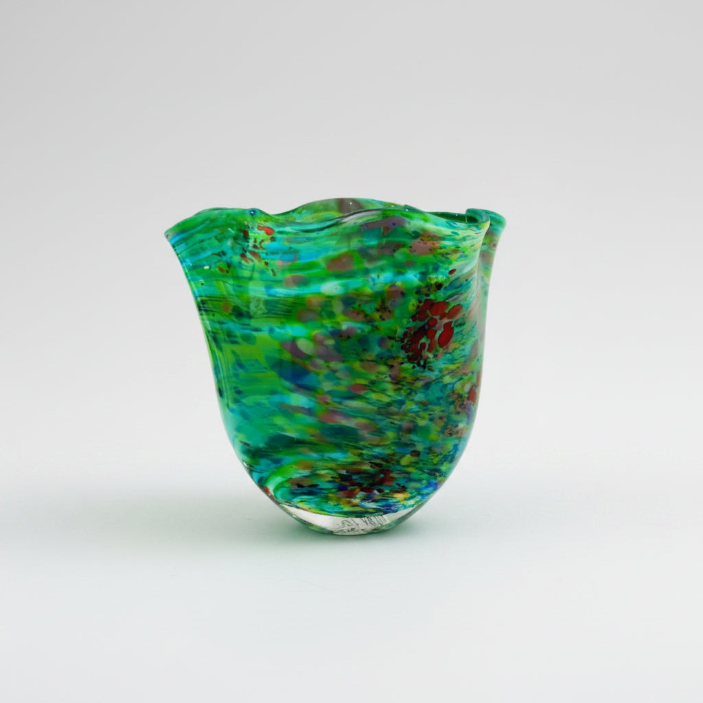 Green glass vase with multicolor speckles on a white background