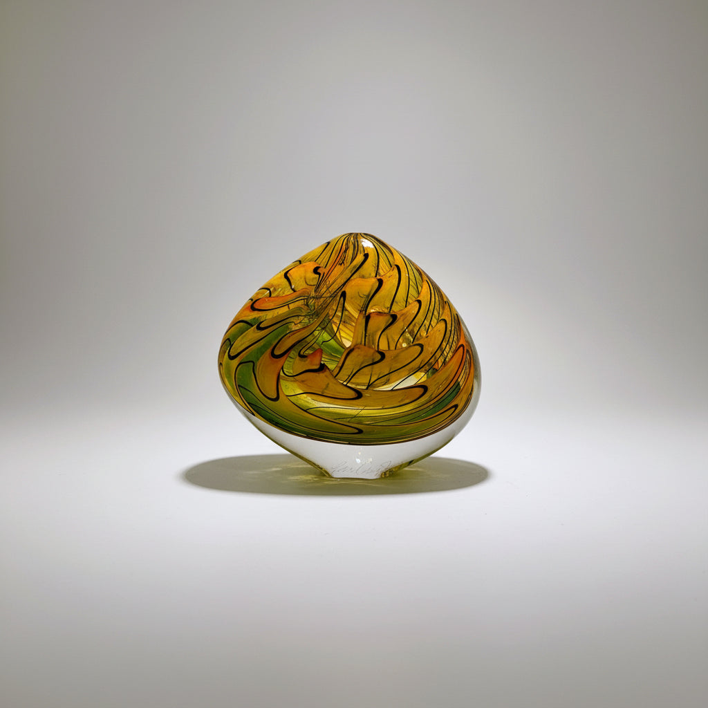 Decorative glass piece with swirling patterns on a white surface
