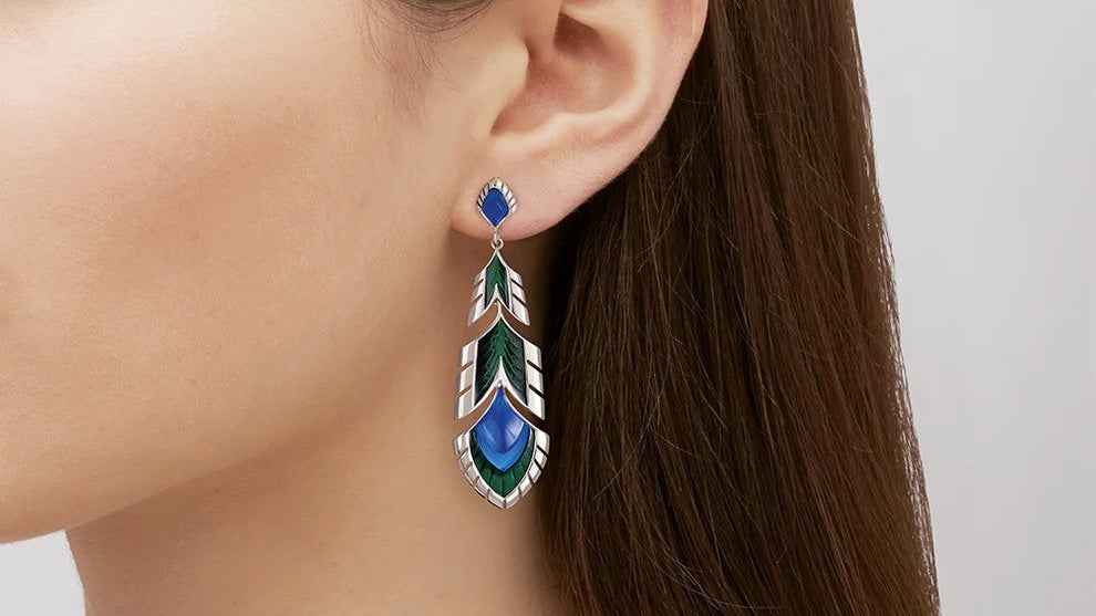 Close-up of a woman wearing a pair of Lalique earrings with a geometric design on a neutral background