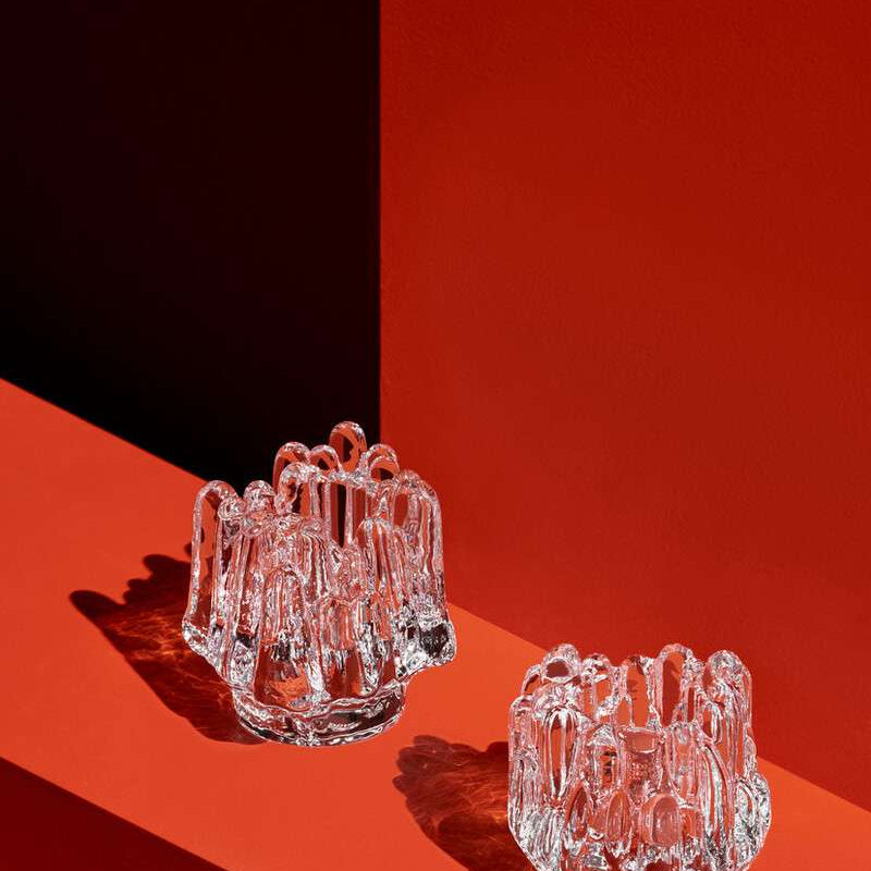 Two clear glass candle holders on a red and black background