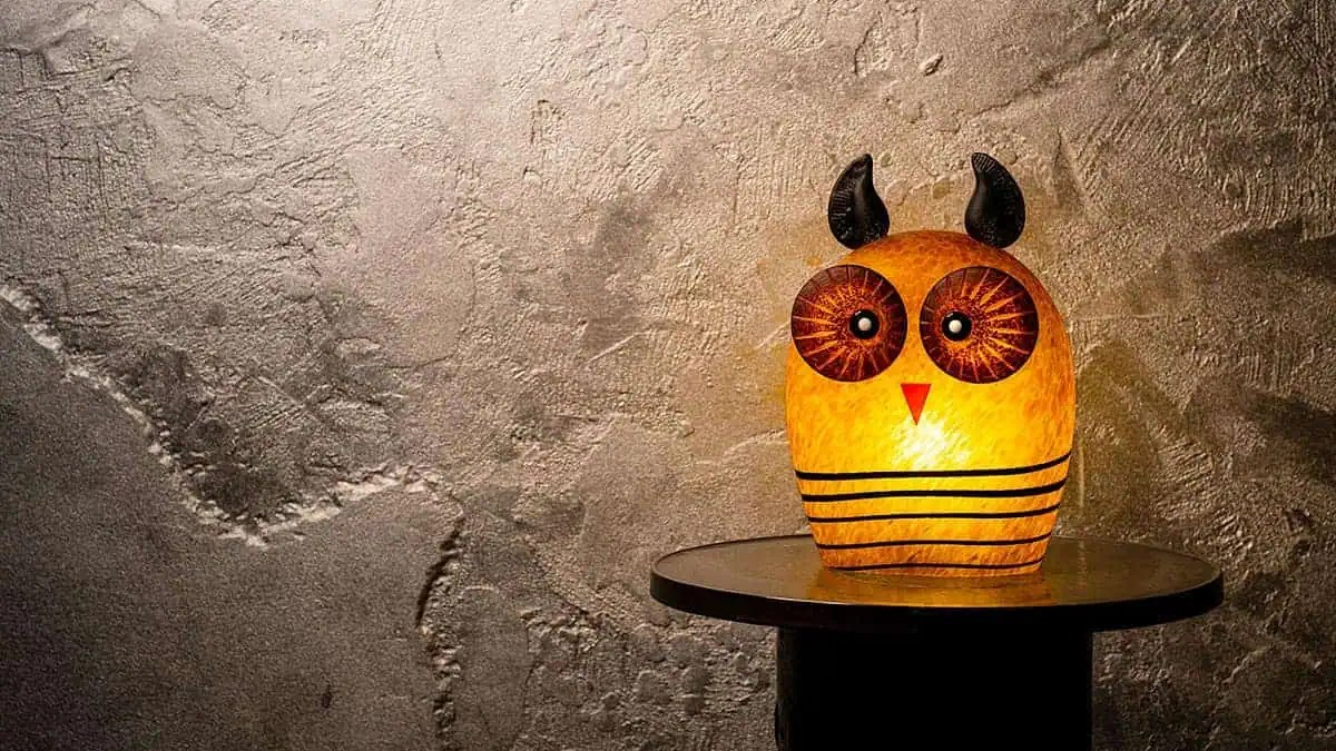 Borowski Glass Owl-shaped lamp on a small round table against a textured wall.