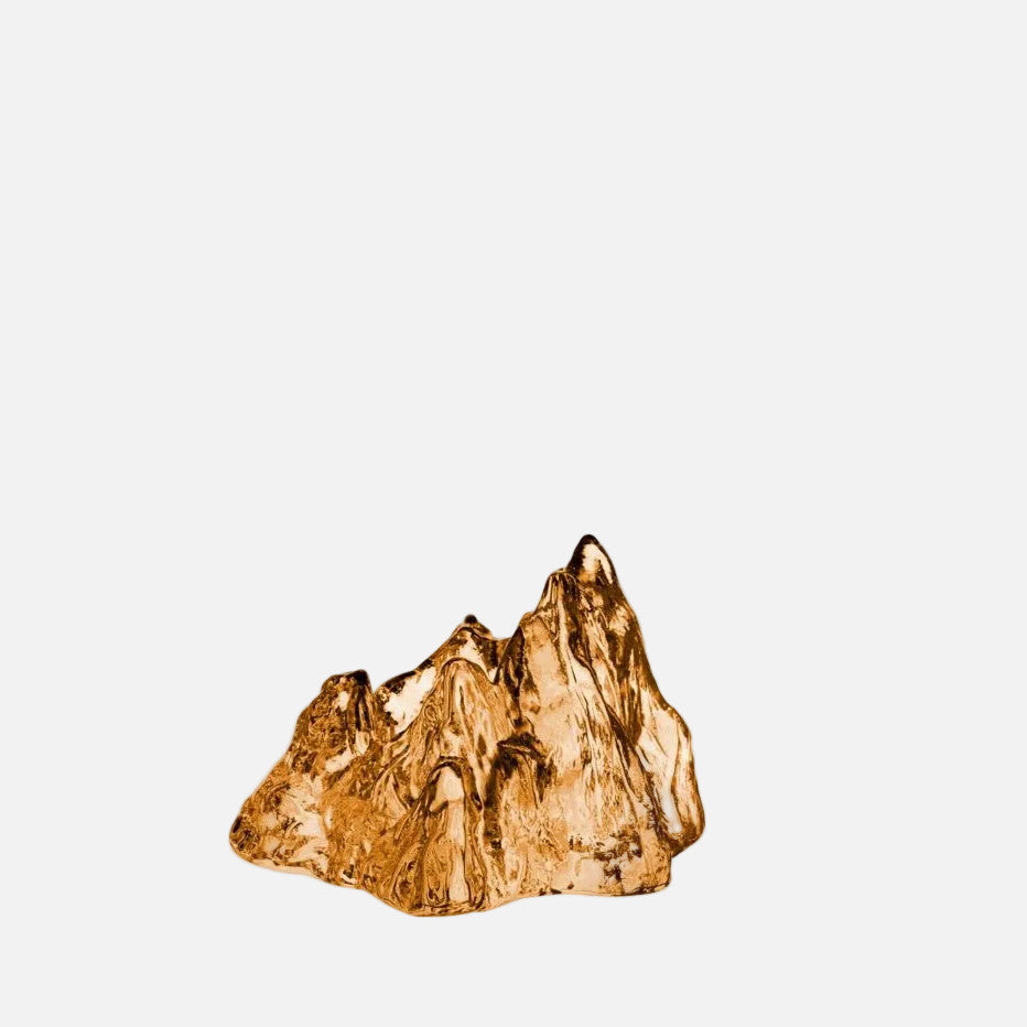A bronze circular glass votive with an irregular, textured surface, resembling a rock.