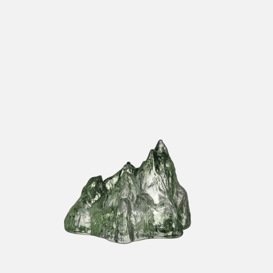 A green glass sculpture with an irregular, mountain-like shape.