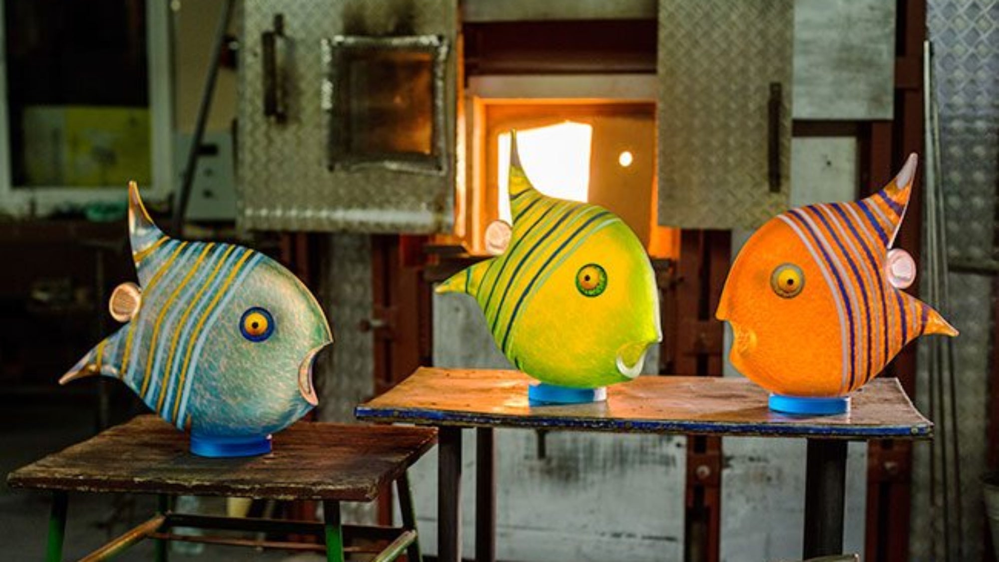Borowski Angel colourful fish sculptures on wooden tables with a workshop background