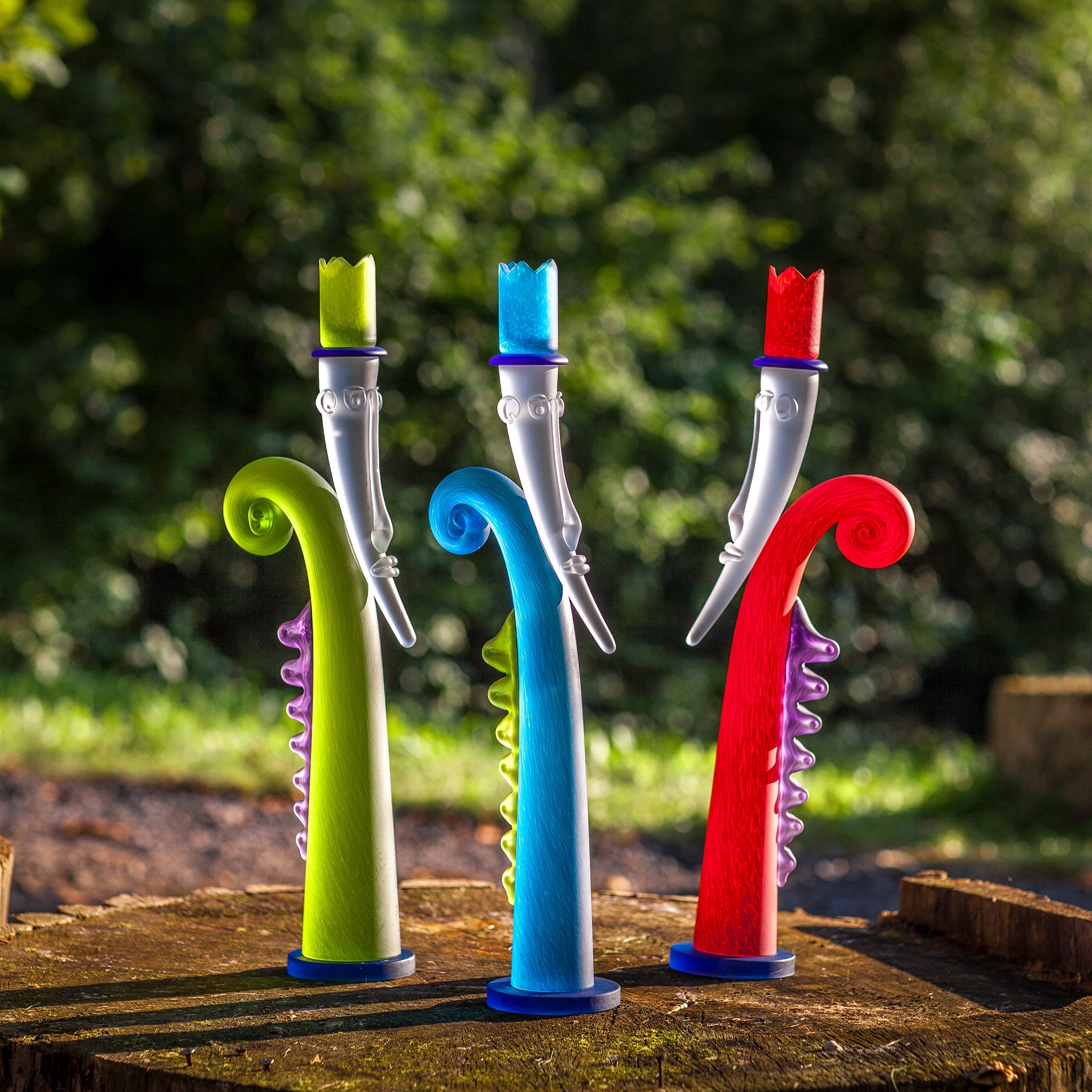 Colourful candleholders on a wooden surface with a natural background