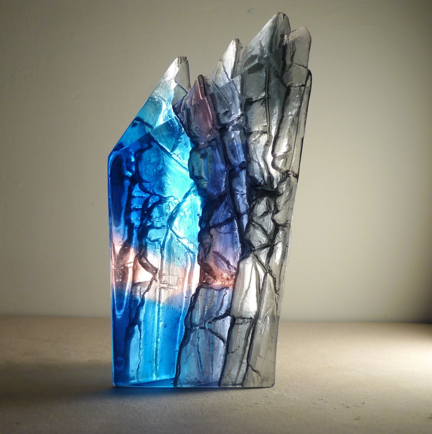 Glass sculpture with blue and gray colors on a plain background
