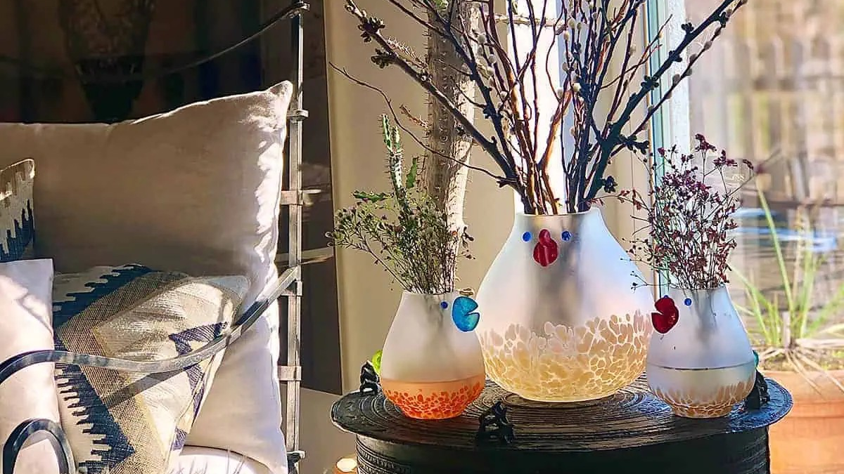 Borowski Glass vases with plants on a table by a window