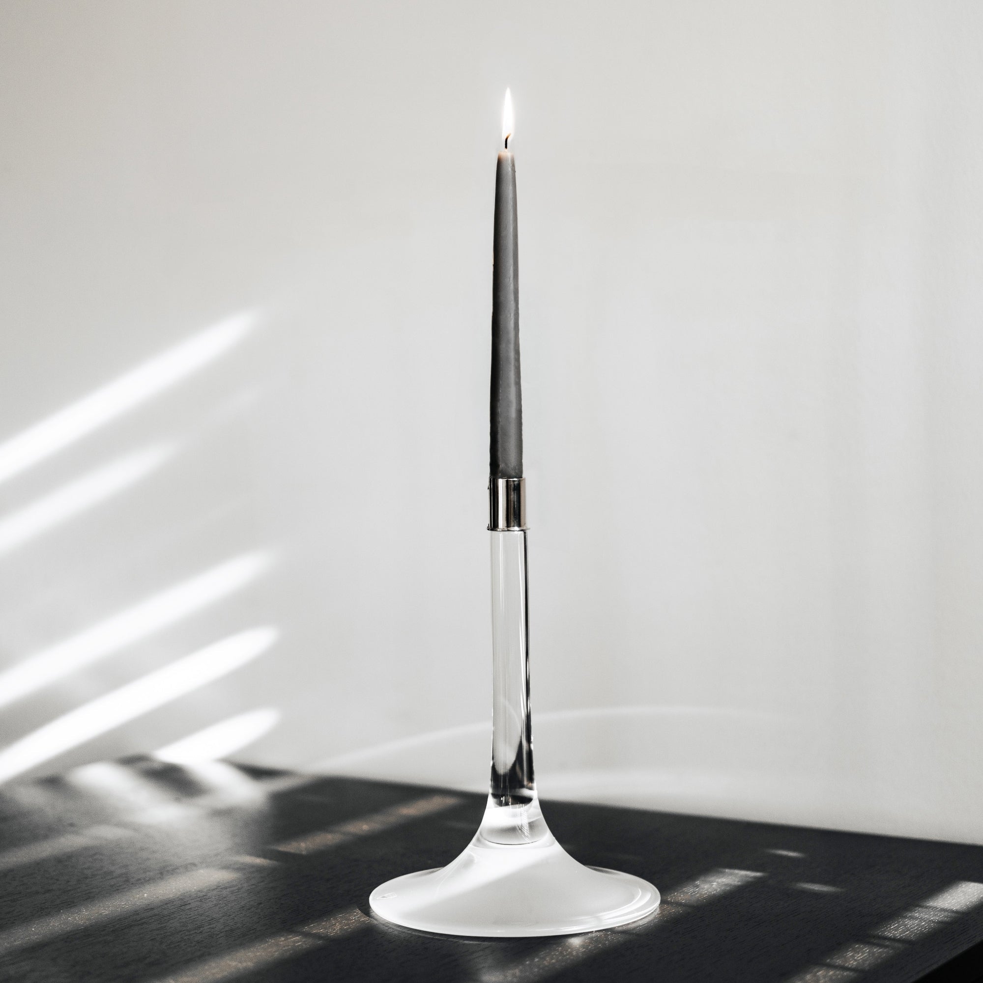 Orrefors Cirrus Candle in a modern holder on a reflective surface with a light background
