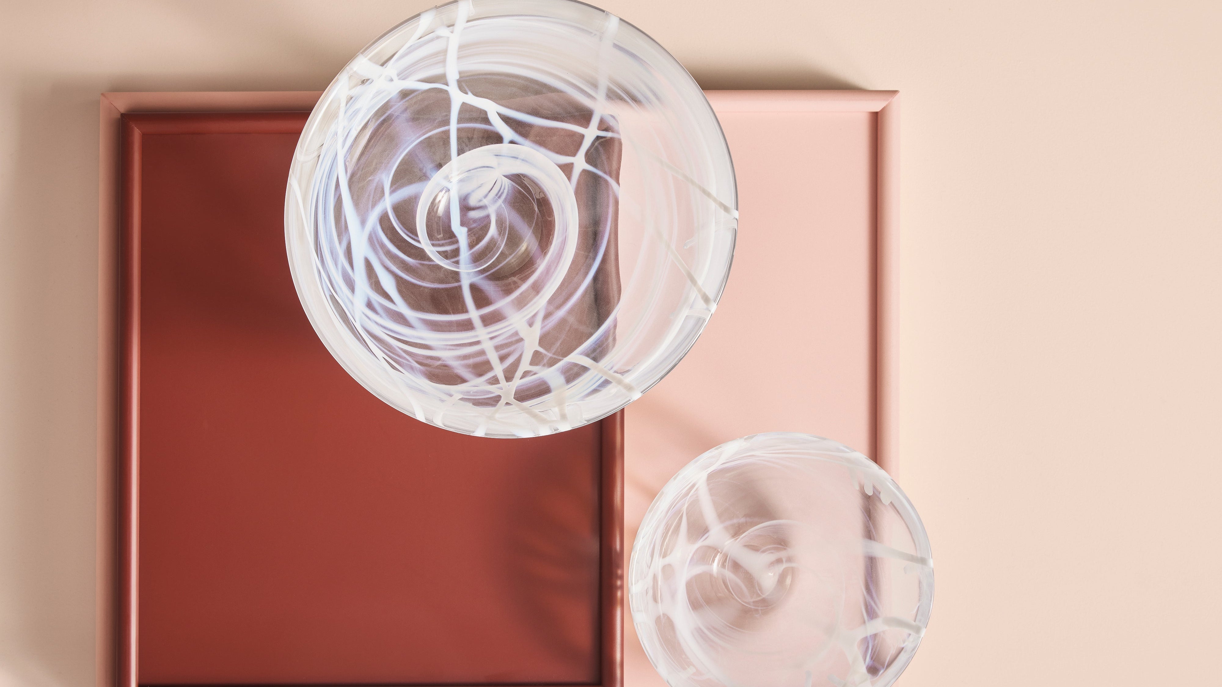 Two glass bowls on a pink and brown box against a beige background