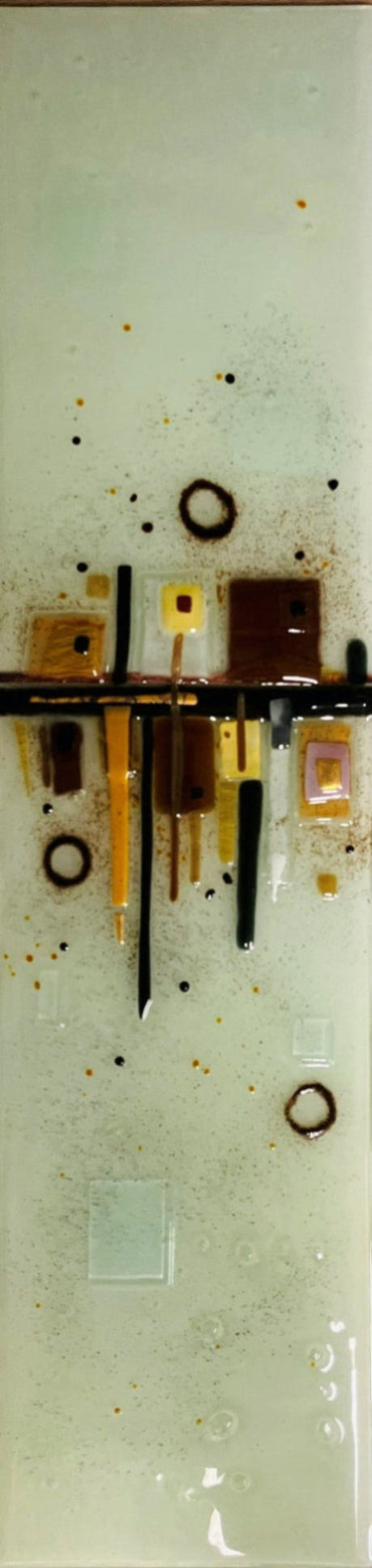 Wall glass art - square glass art piece featuring a horizontal black bar with various coloured glass elements, including brown, yellow, orange, and black, set against a pale greenish-grey background with small gold flecks.