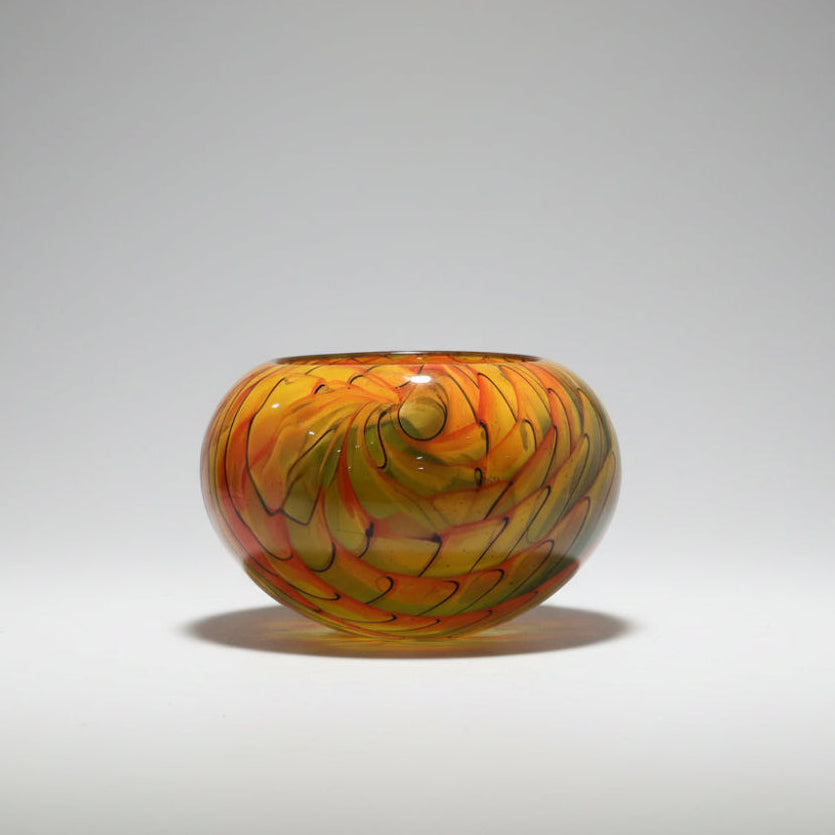 Colorful glass bowl on a white surface with a neutral background