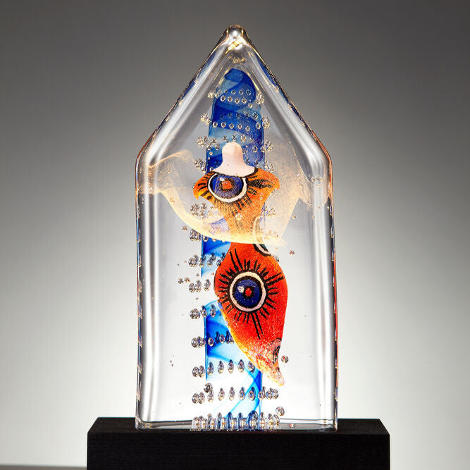 Decorative art glass piece with colorful design on a black base against a gray background