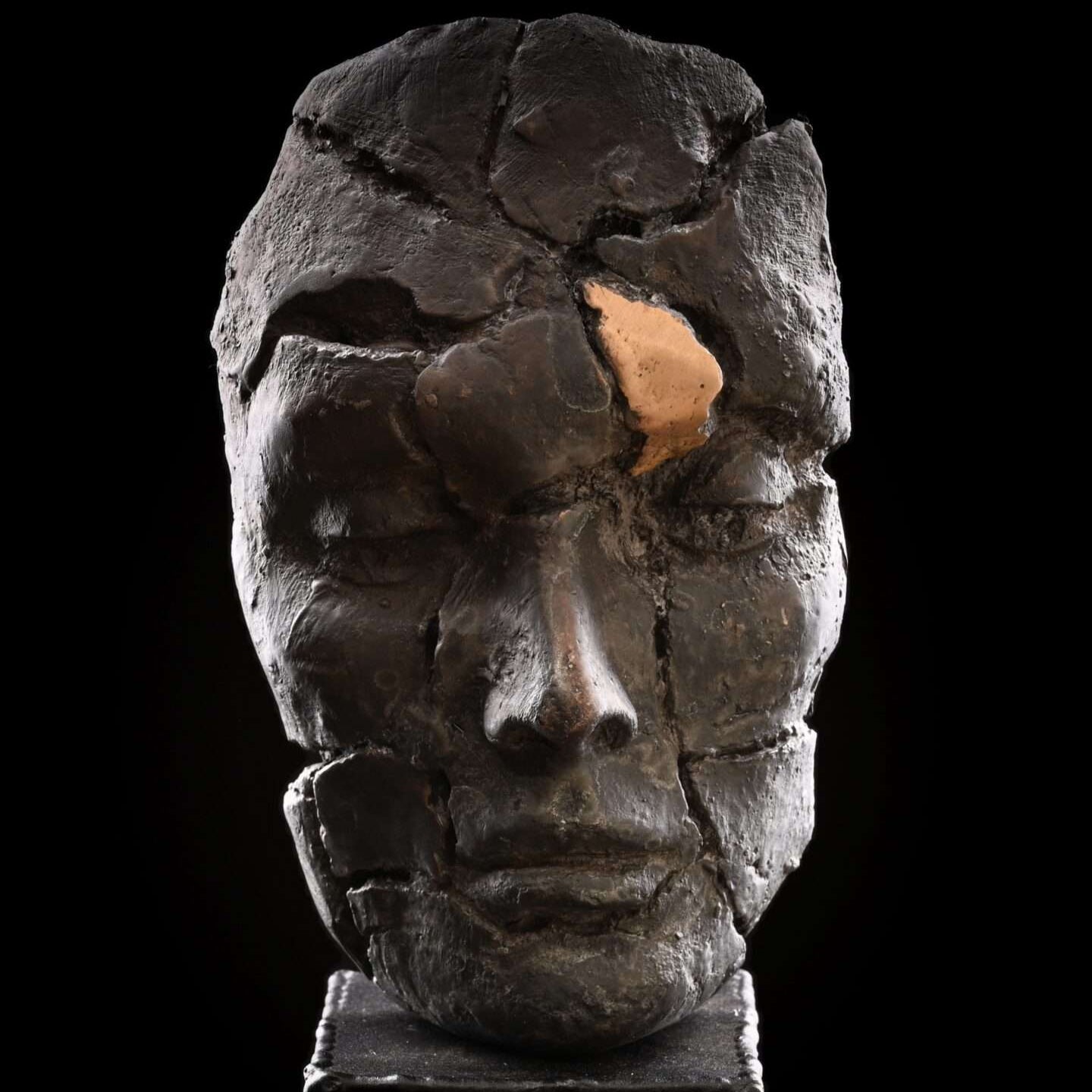 Bronze sculpture of a human head with a gold patina detail on the eye socket.