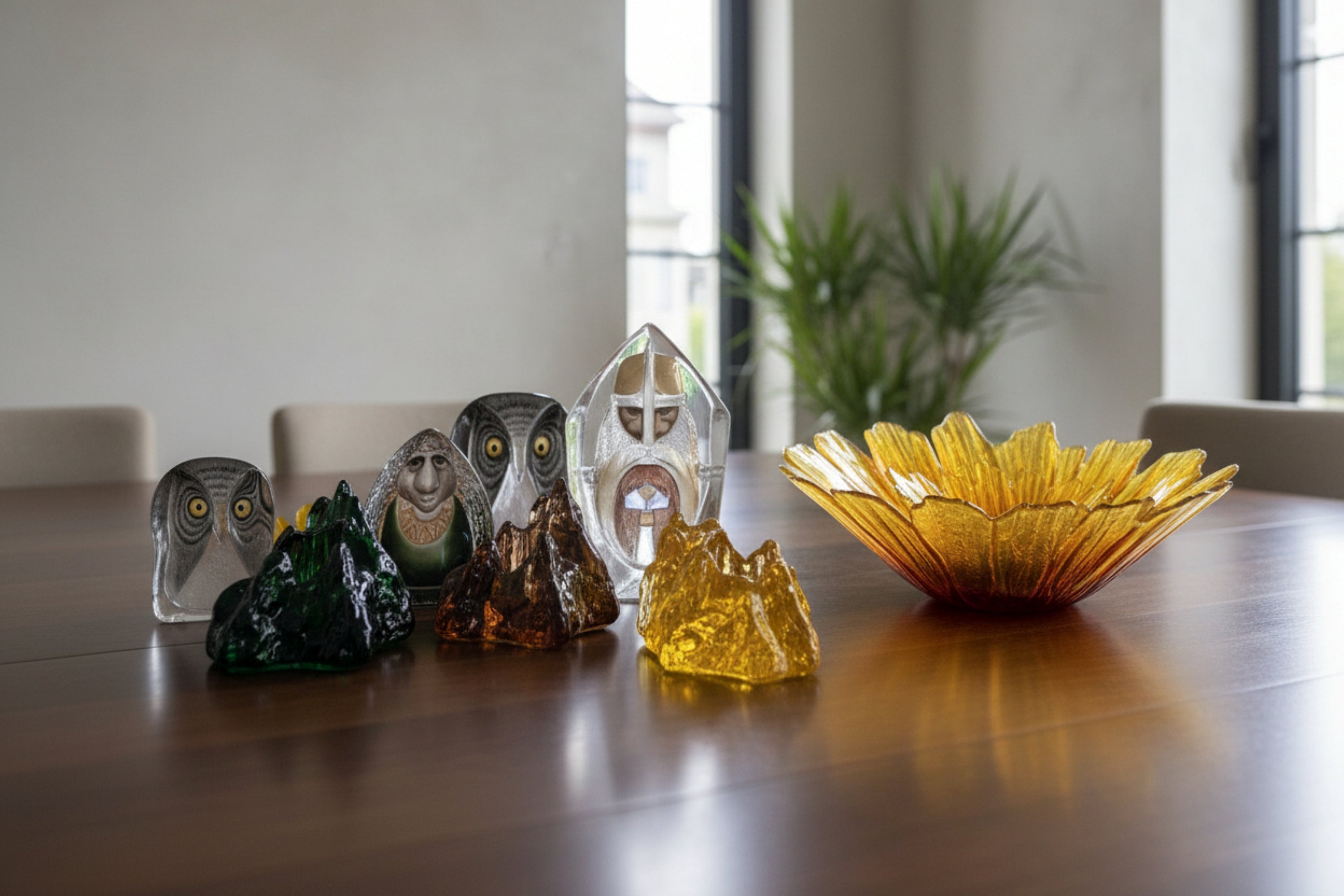 Lifestyle mix - Maleras and Kosta Boda  collection of decorative glass sculptures and a translucent yellow flower-shaped bowl 