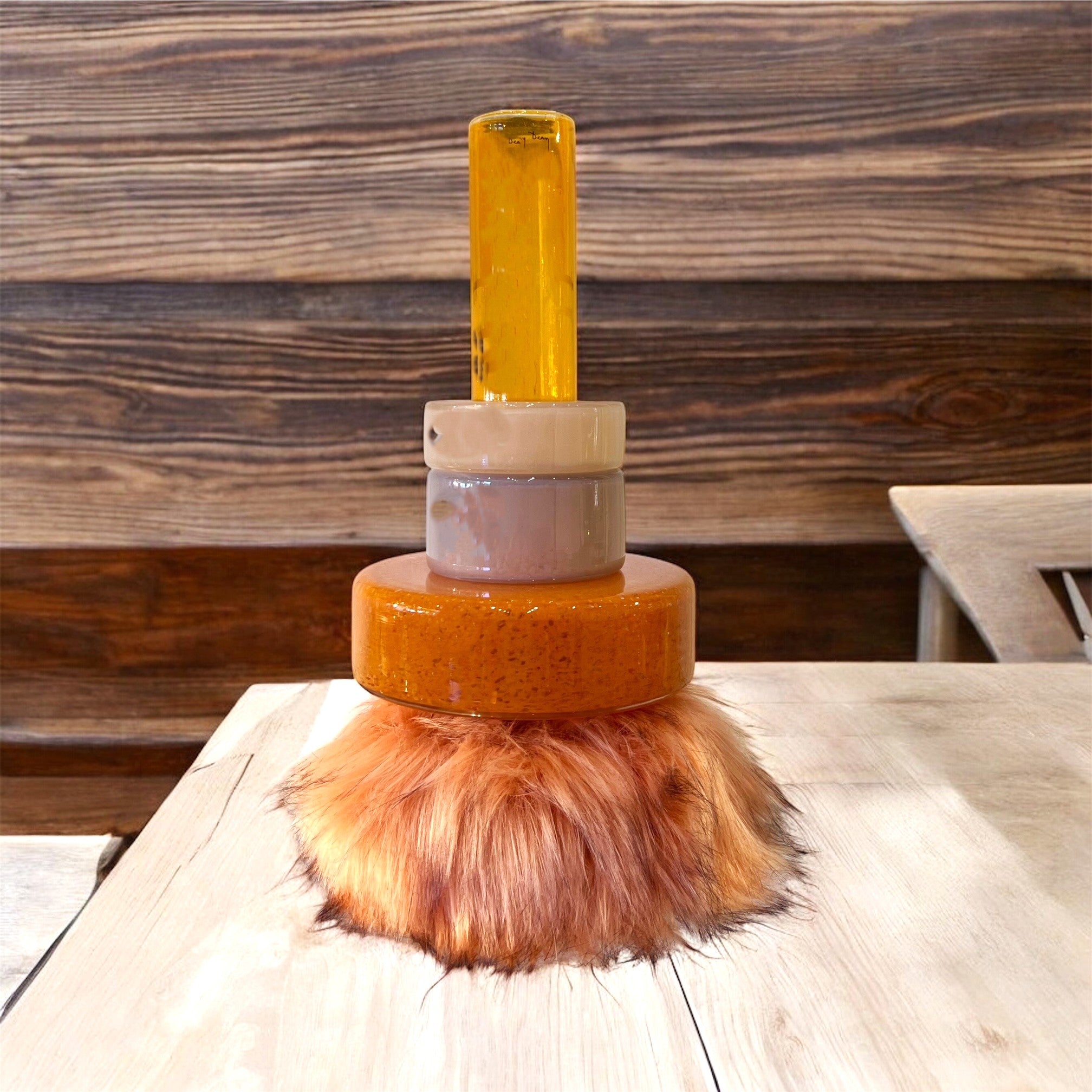 Shaving brush with yellow handle and brown bristle head on a wooden surface