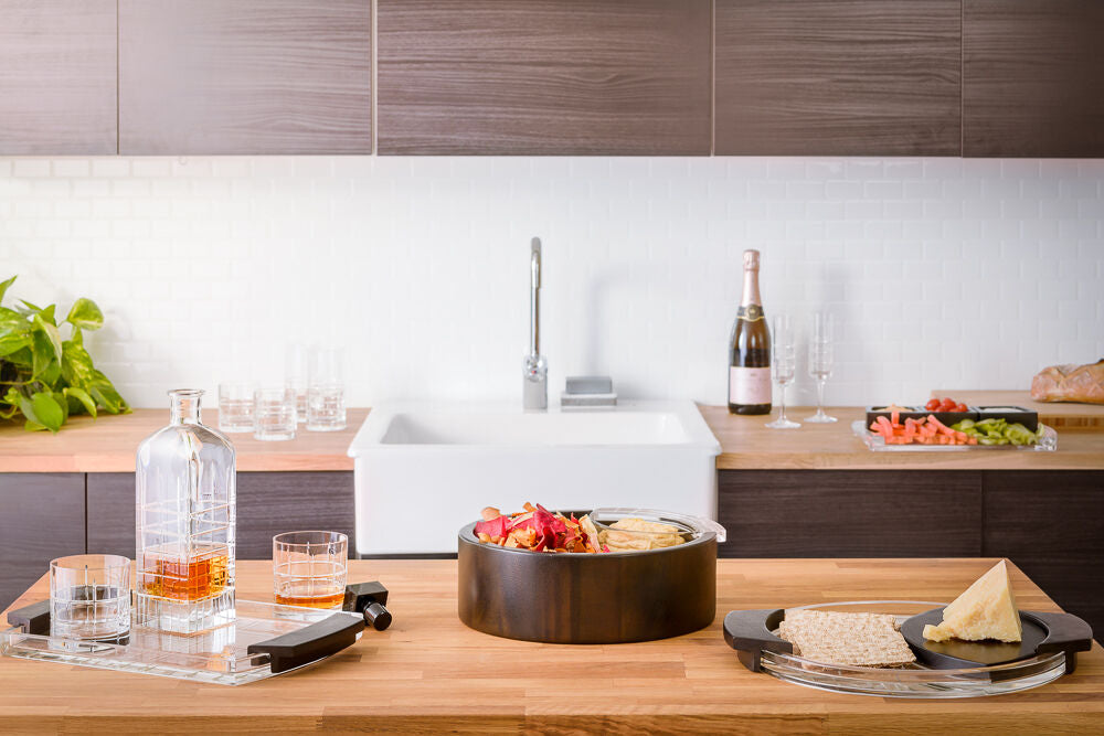 Orrefors Street glasses Modern kitchen with wooden countertops, a sink, and various items including a bottle of champagne and a plate of food.