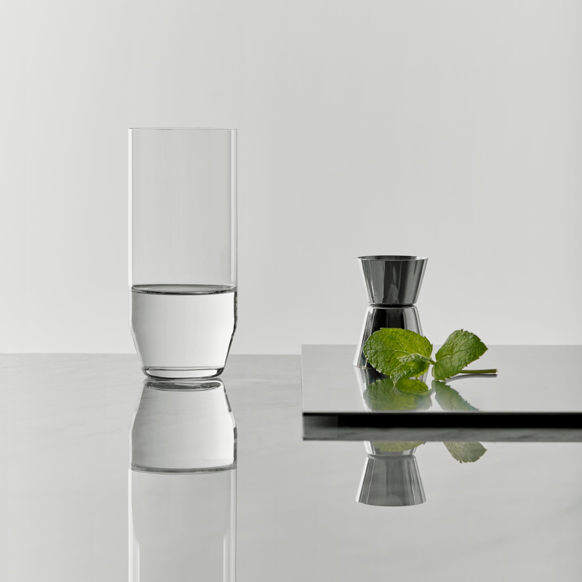 Frantzen glass of water on a reflective surface with a white background