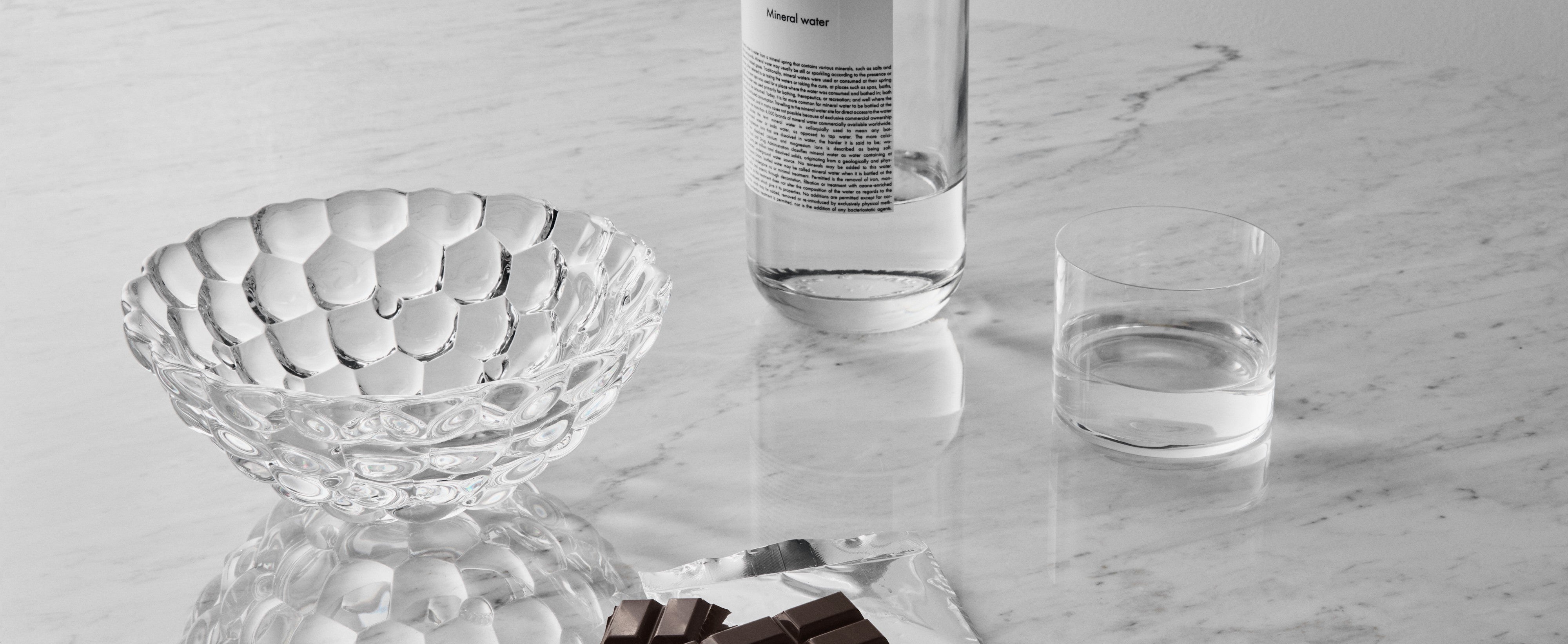 Glass bowl, chocolate bar, and glass of water on a marble surface