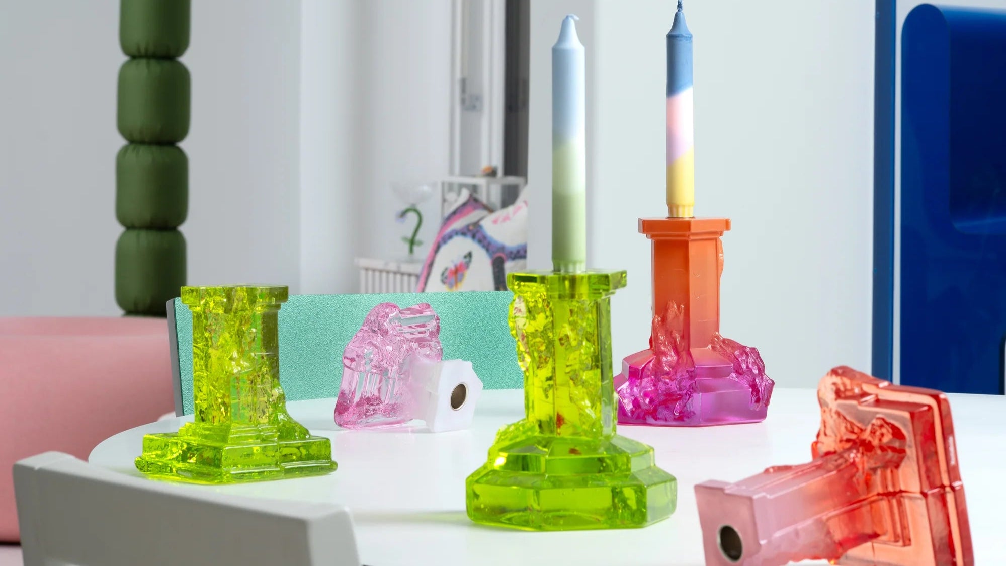 Colorful candle holders on a table with a palm tree decoration in the background.