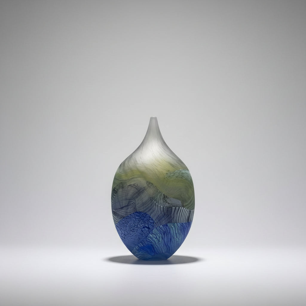 Glass vase with multicolored design on a white surface and beige wall background