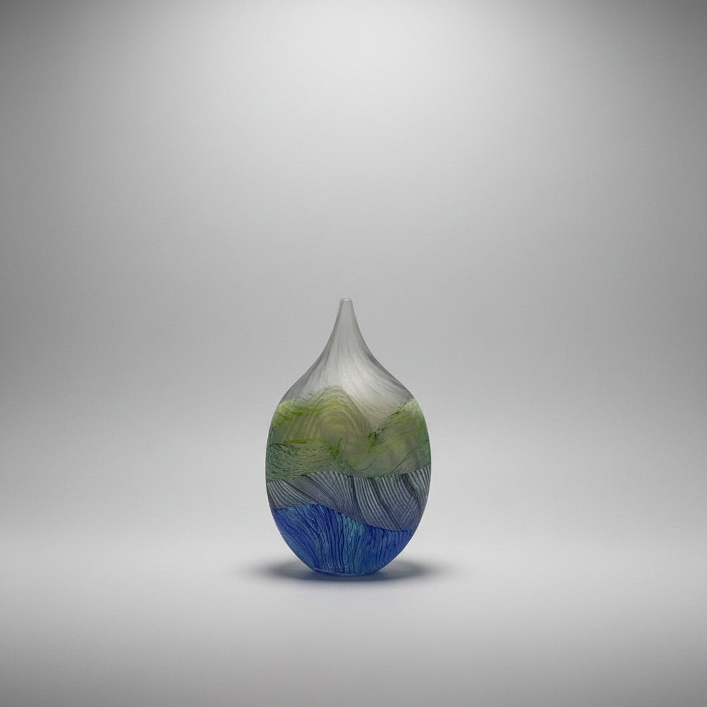 Glass vase with blue and green patterns on a white platform
