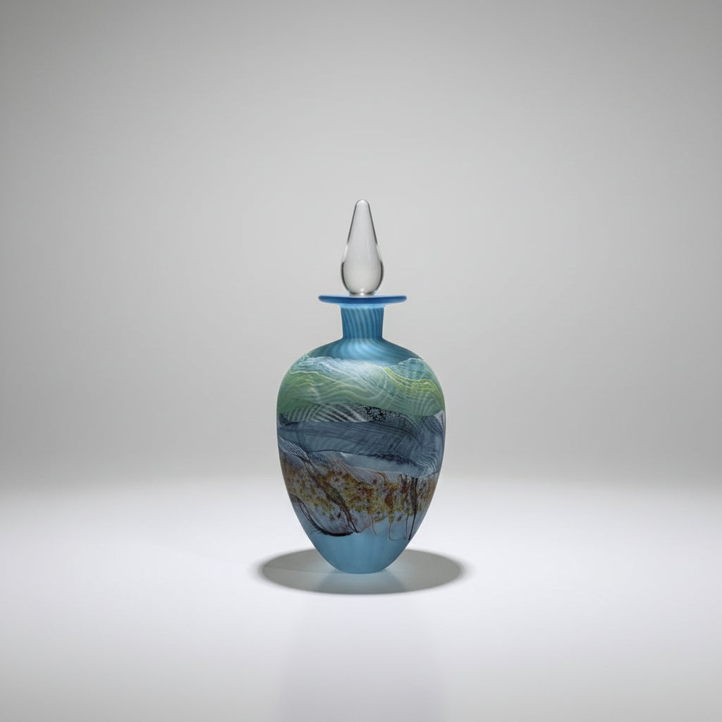 Thomas Petit Decorative glass bottle with a white stopper on a white platform against a plain background