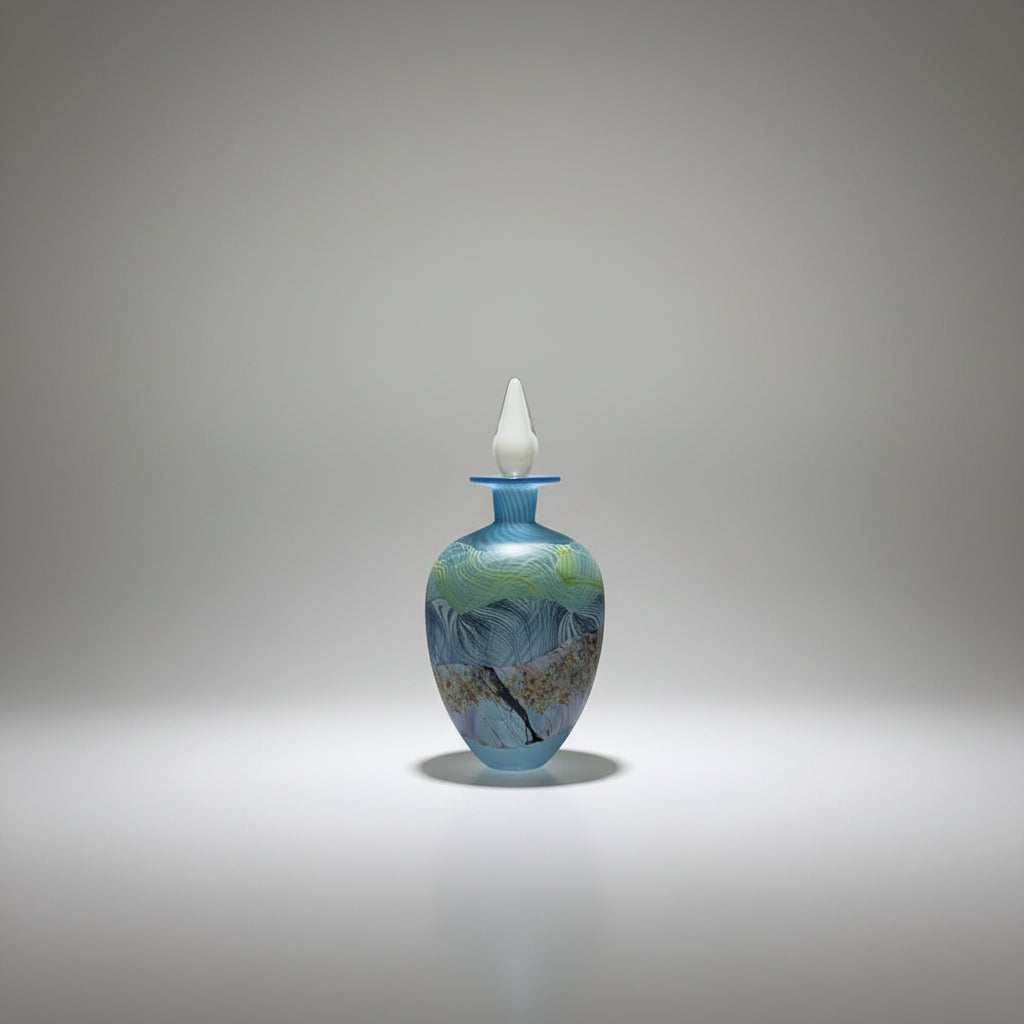 Thomas Petit Glass bottle with a white stopper on a white platform against a plain background