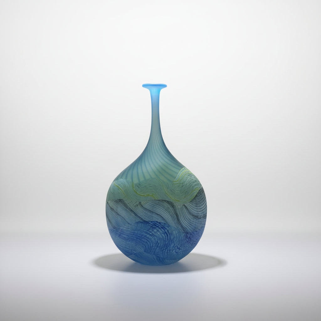 Thomas Petit Sea shore Blue and green glass vase on a white platform with a neutral background 
