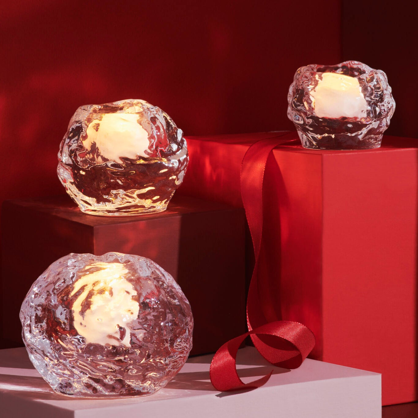 Three snowballs crystal candle holders with lit candles on a red and brown background
