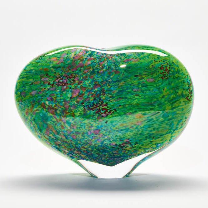 Heart-shaped glass piece with green and multicolor pattern on a white background